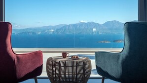 Una habitación con dos sillas orientadas a un amplio ventanal que ofrece una vista panorámica de montañas y el mar.