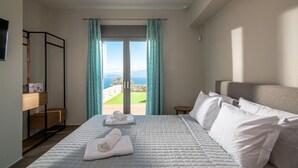 Habitación de hotel con cama, vista al mar y balcón.