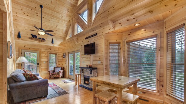 A log cabin interior with a sofa, dining table, and fireplace.