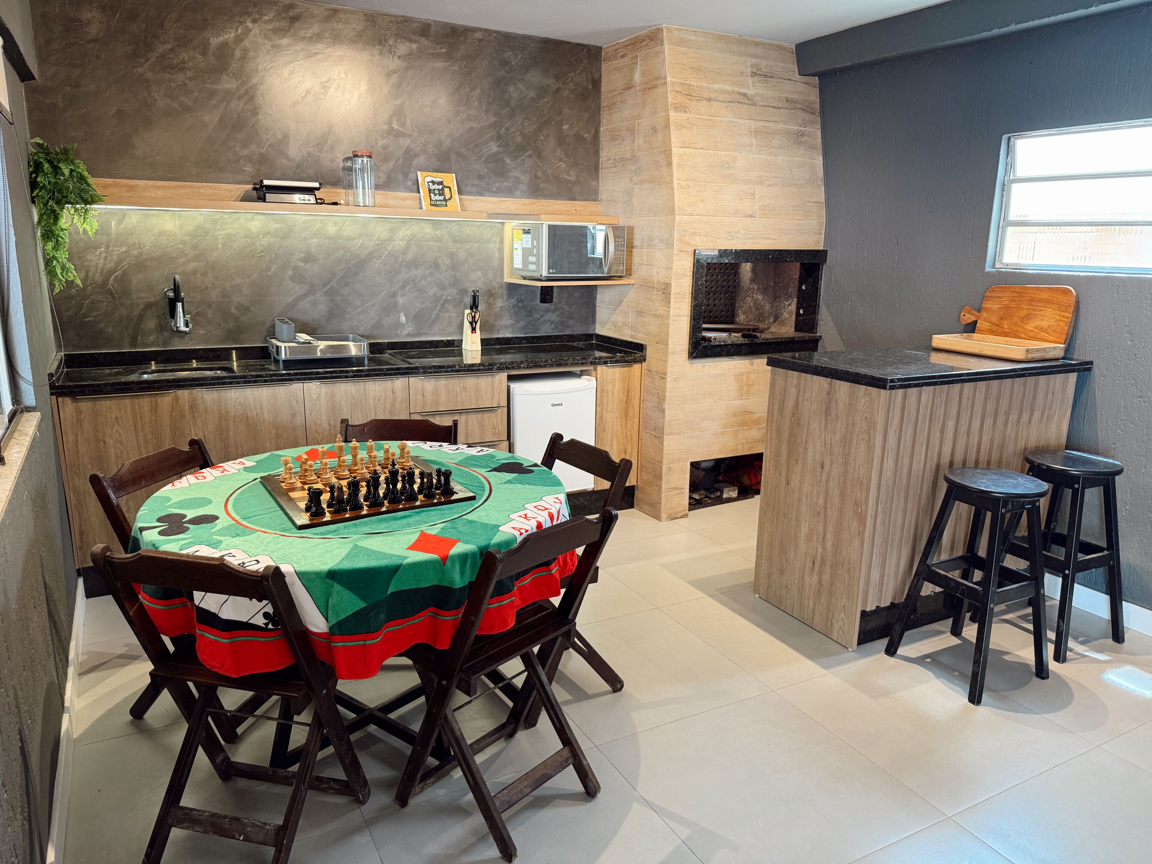 A modern kitchen with a chessboard on the table, a microwave, and a coffee machine.