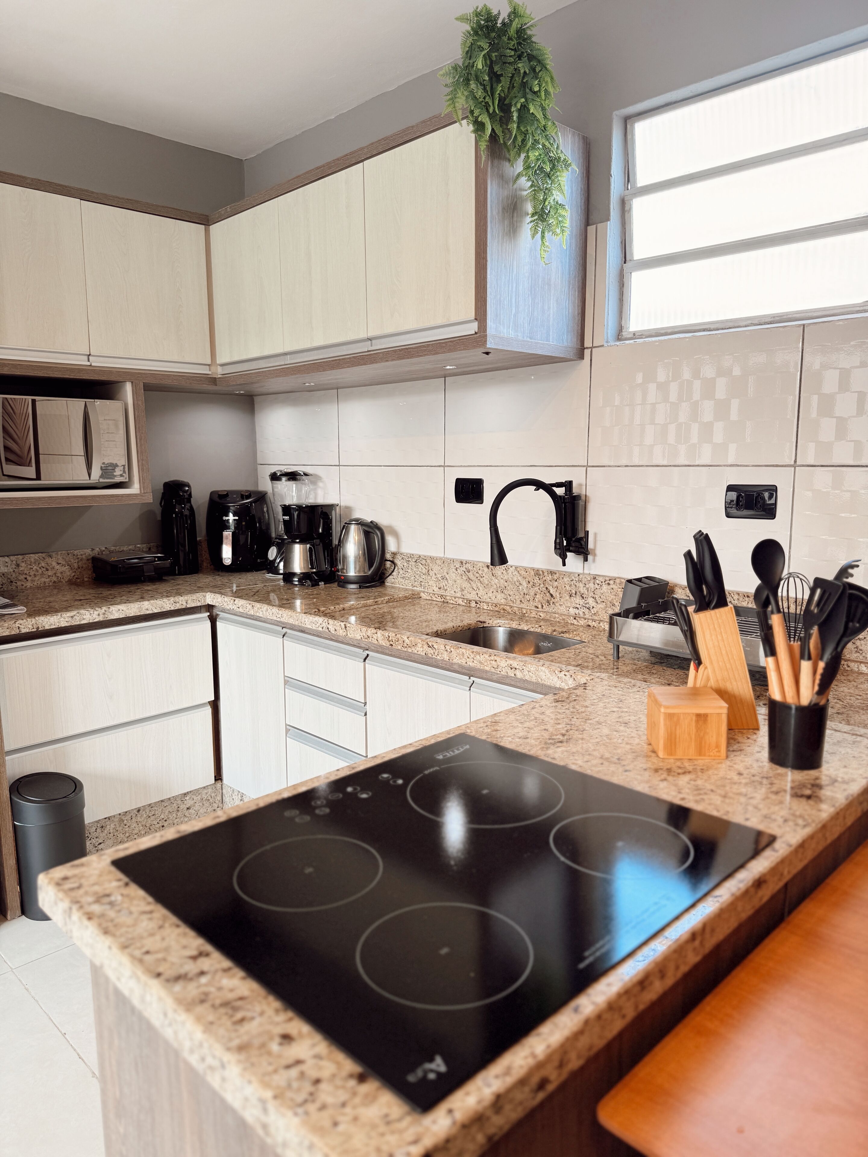A modern kitchen with a built-in stove, a coffee maker, and a sink.