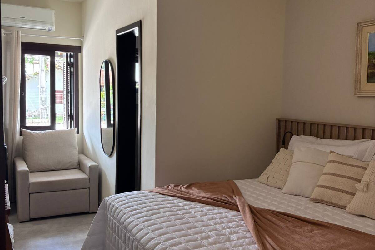 A bedroom with a bed, a chair, a ceiling fan, and a door.