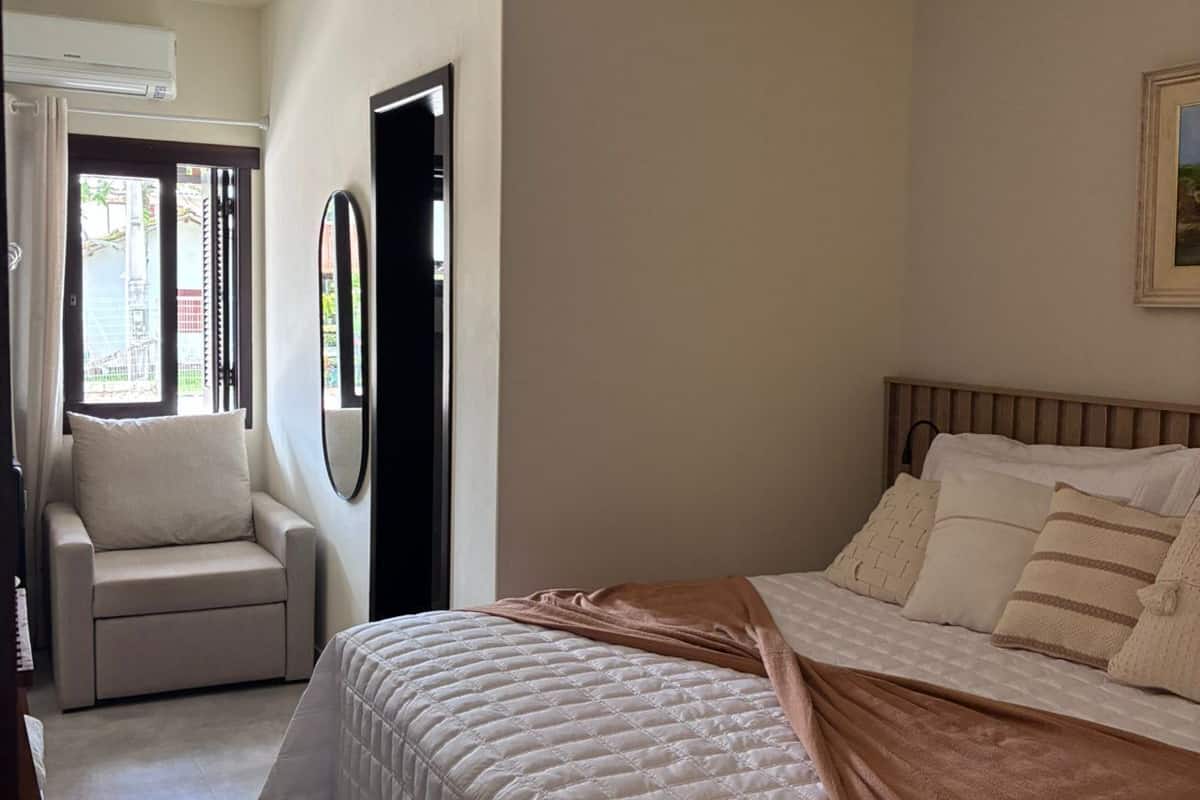A bedroom with a bed, a chair, a ceiling fan, and a door.