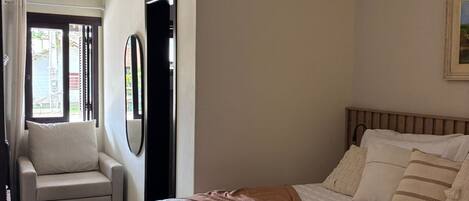 A bedroom with a bed, a chair, a ceiling fan, and a door.