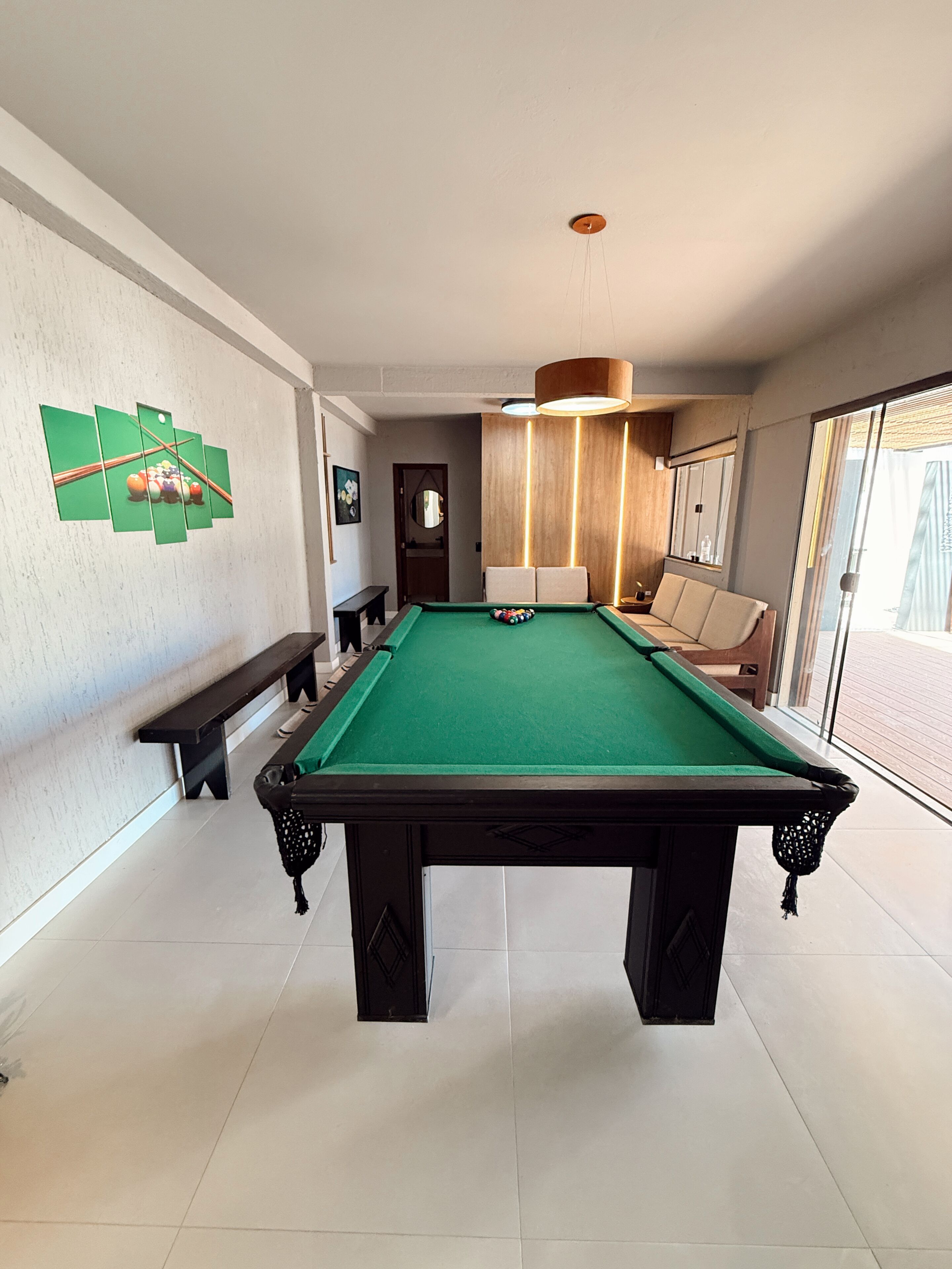 Ein Billardtisch in einem Raum mit einer Bank, einem Sofa und einer Tür zu einem Balkon.