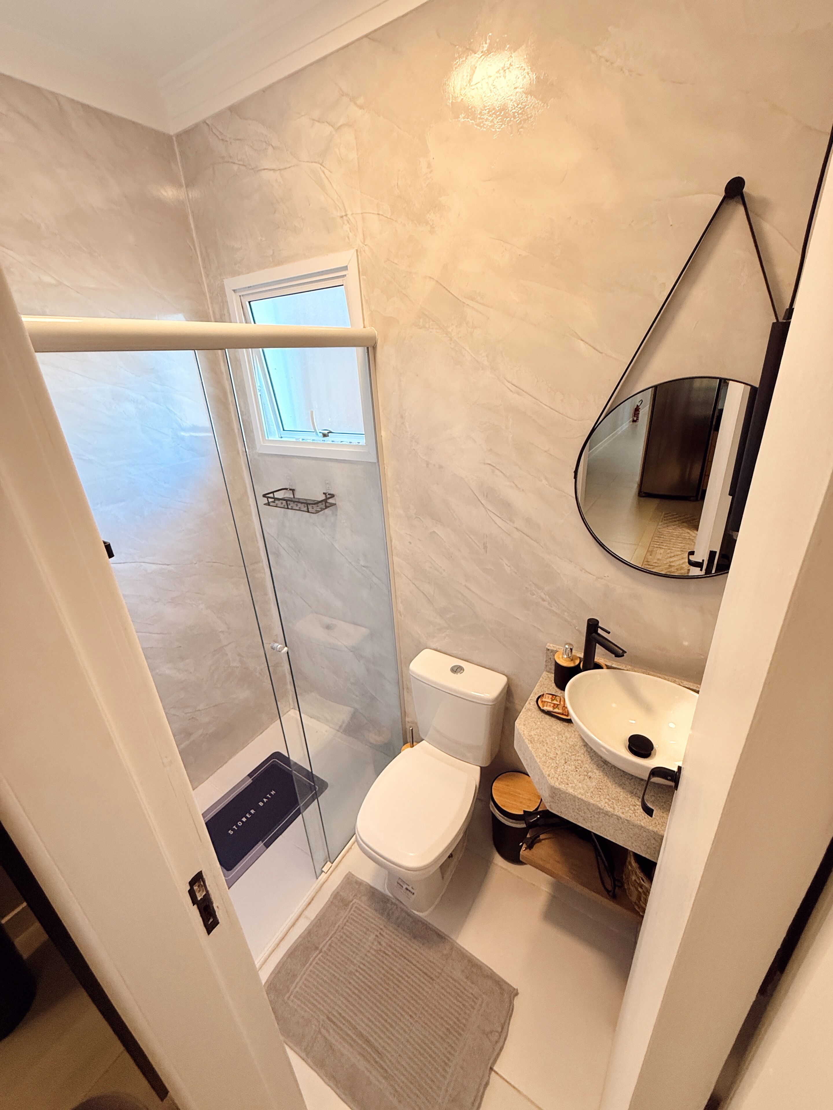 A bathroom with a shower, toilet, sink, and a mirror.