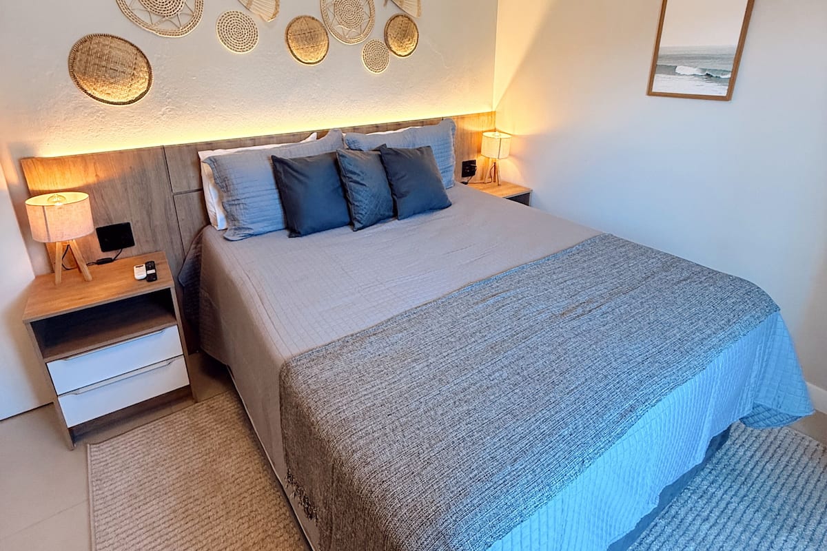 A bedroom with a bed, bedside tables, a wall-mounted mirror, and decorative wall art.