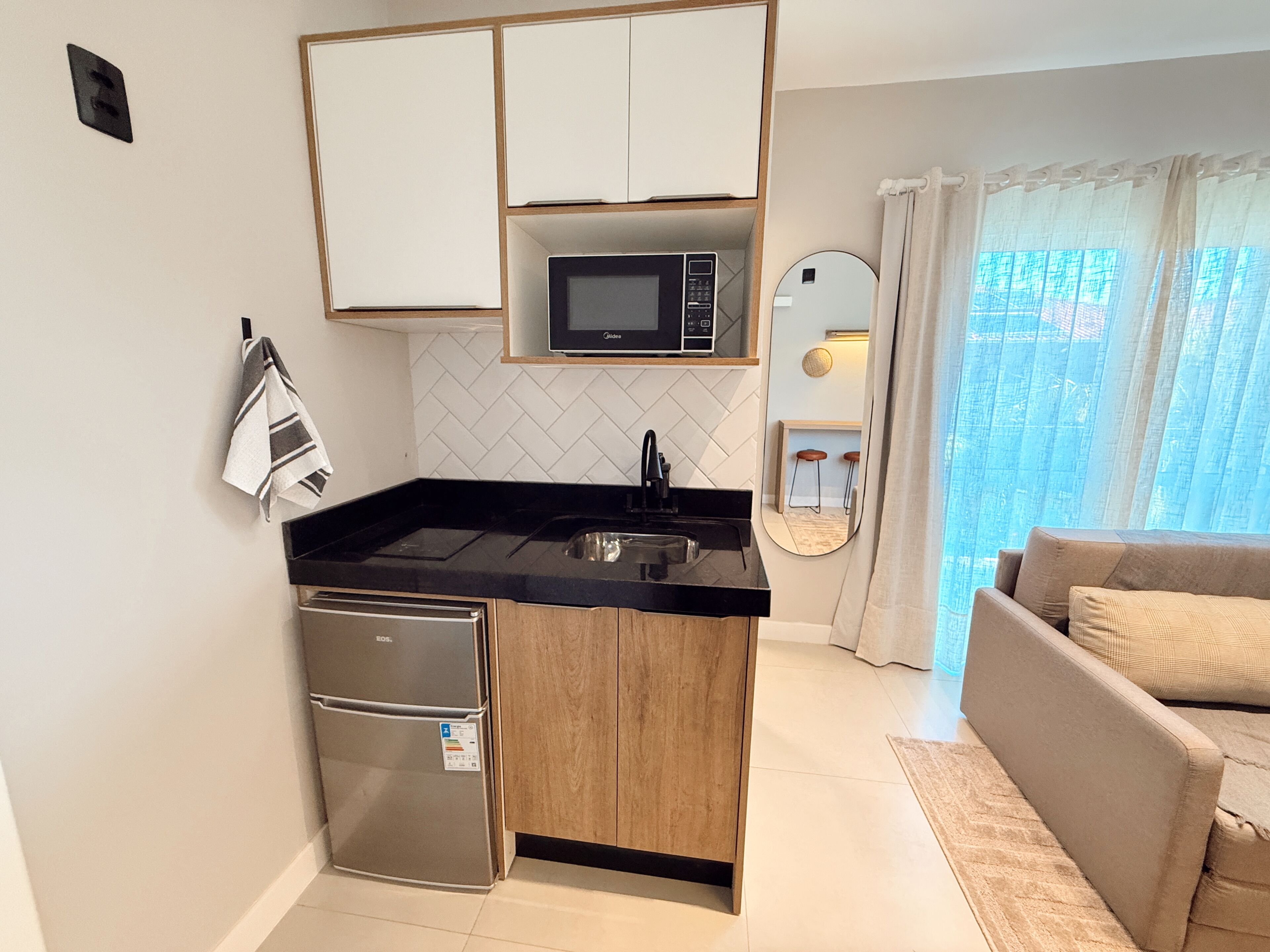 A compact kitchen with a microwave, sink, and refrigerator.