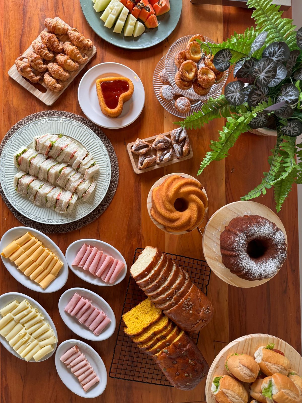 A variety of pastries and sandwiches on a wooden table.