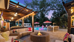 Un patio exterior con un pozo de fuego, asientos y una zona de piscina.