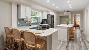 Una cocina moderna con armarios blancos, un refrigerador negro y una encimera de mármol.