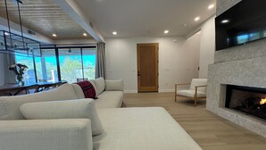 A modern living room with a sectional sofa, a fireplace, and a dining area with a view.