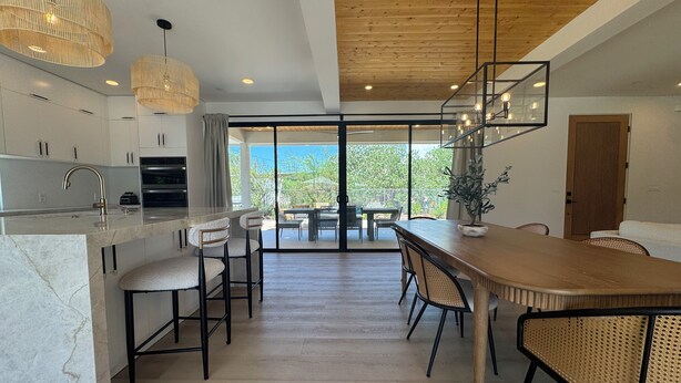 A modern kitchen with a marble countertop, wooden flooring, and a dining area with a wooden table and chairs.