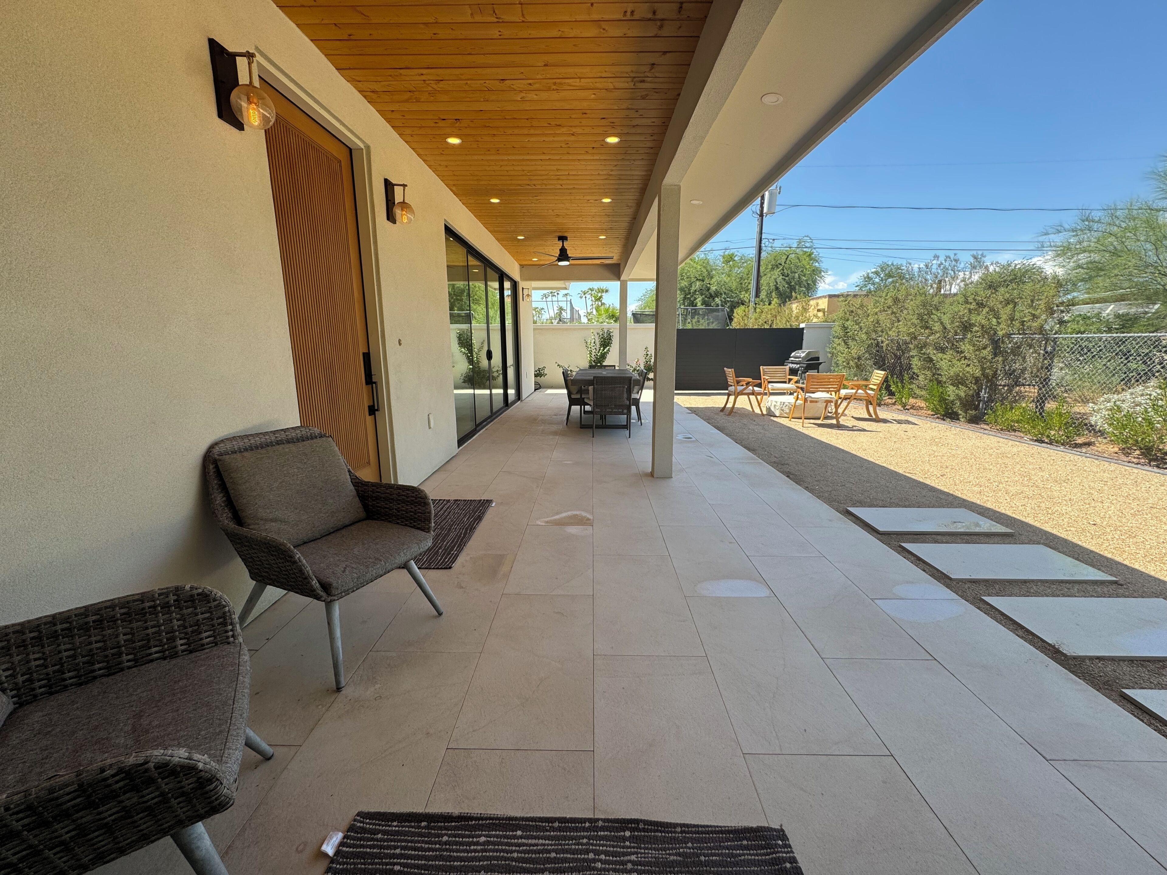 A covered patio with wicker furniture, a ceiling fan, and a view of the backyard.