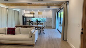A modern living room with a sofa, dining table, and kitchen in the background.