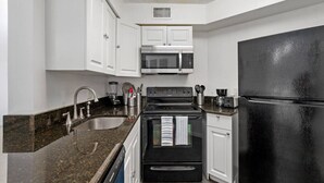 A kitchen with white cabinets, a black refrigerator, a microwave, a stove, and a sink. - Cozy Apt w/ Pool, Hot Tub, Golf, Near Downtown! (Orlando)