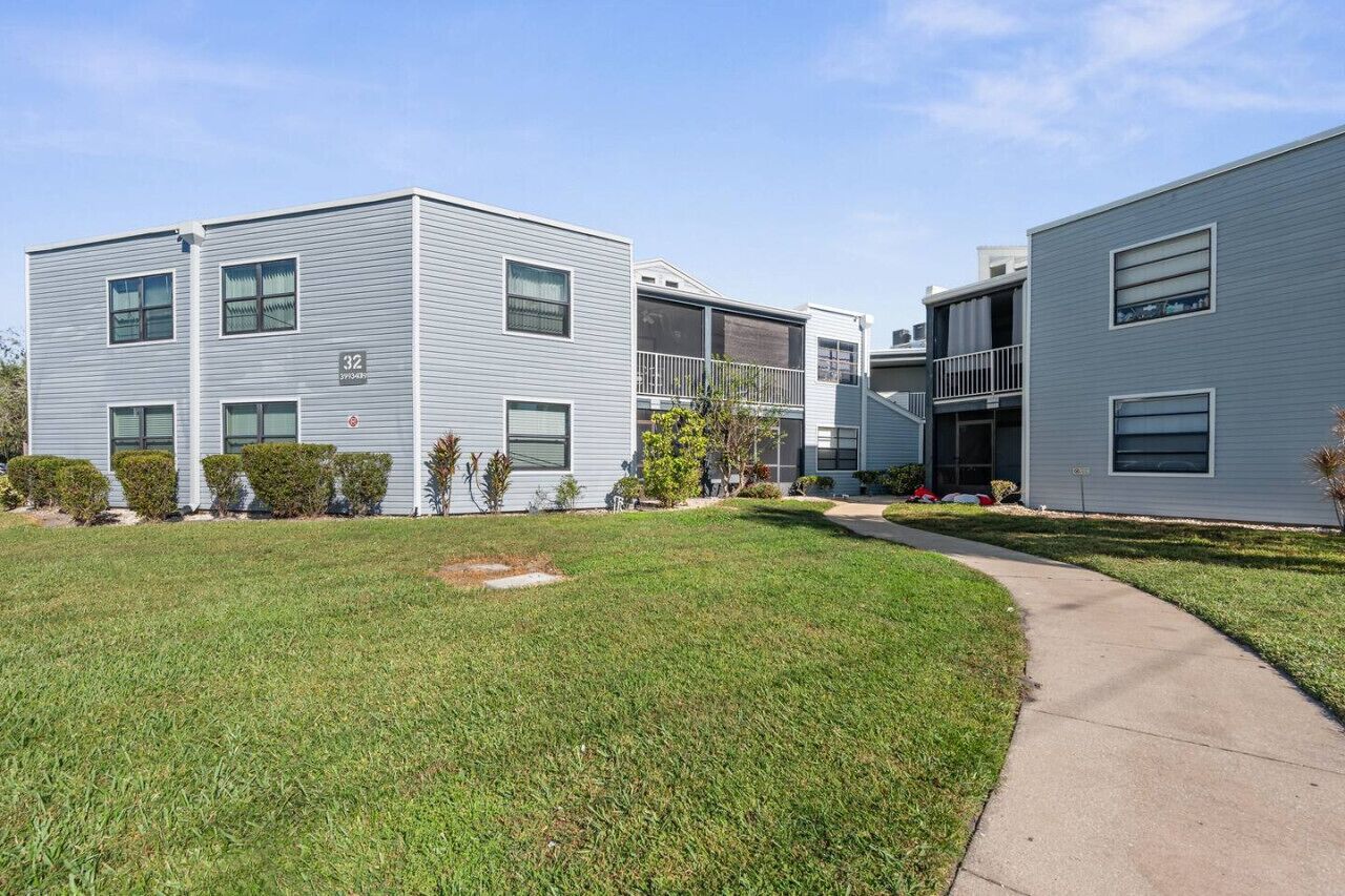 Een modern appartementencomplex met een plat dak, veel ramen en een verzorgd gazon.
