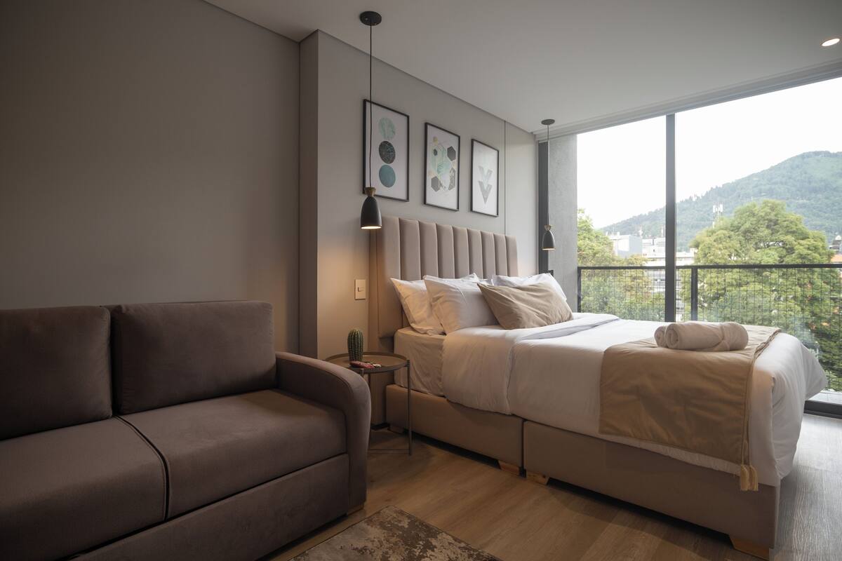 A modern bedroom with a bed, a sofa, and a nightstand.