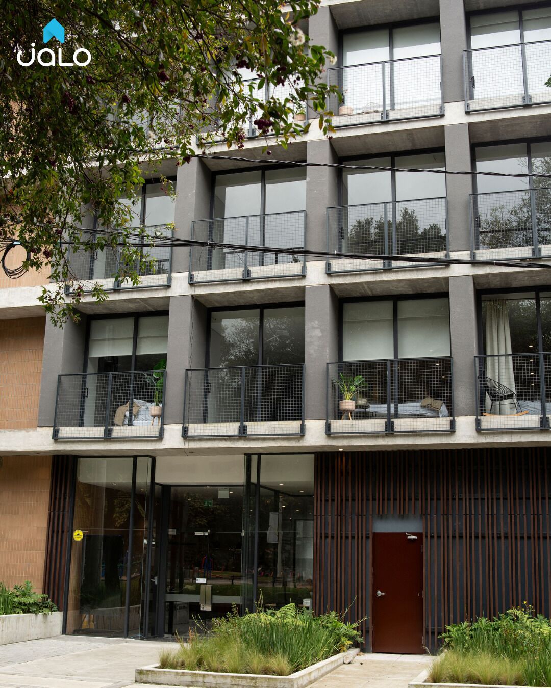 A modern multi-story building with balconies, large windows, and a minimalist design.
