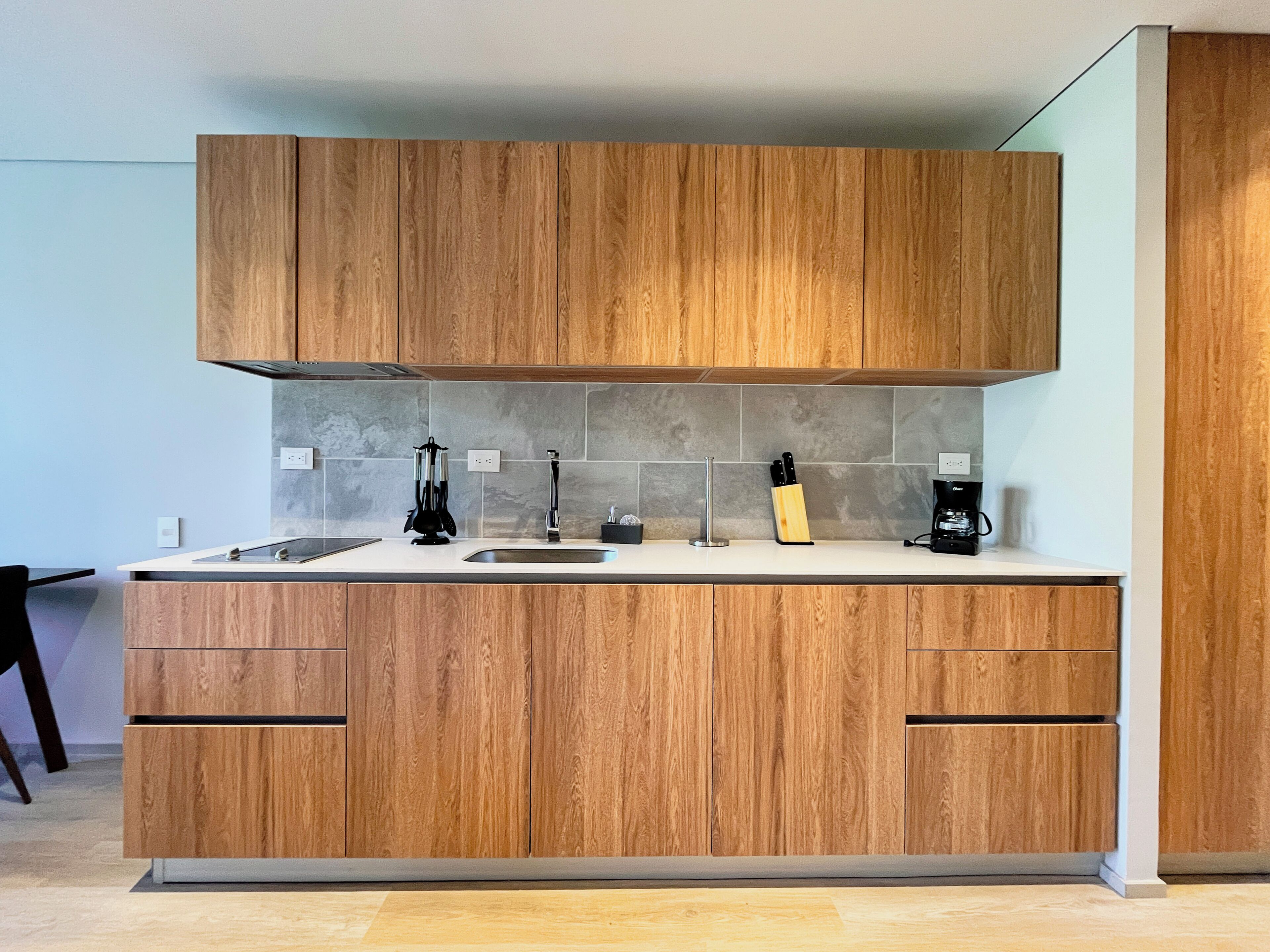 Una cocina moderna con armarios de madera, un lavamanos de acero inoxidable y una cafetera.