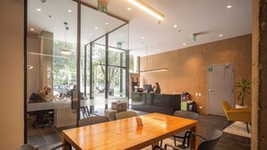 Una sala de conferencias moderna con una mesa de madera, sillas negras y un panel de vidrio.