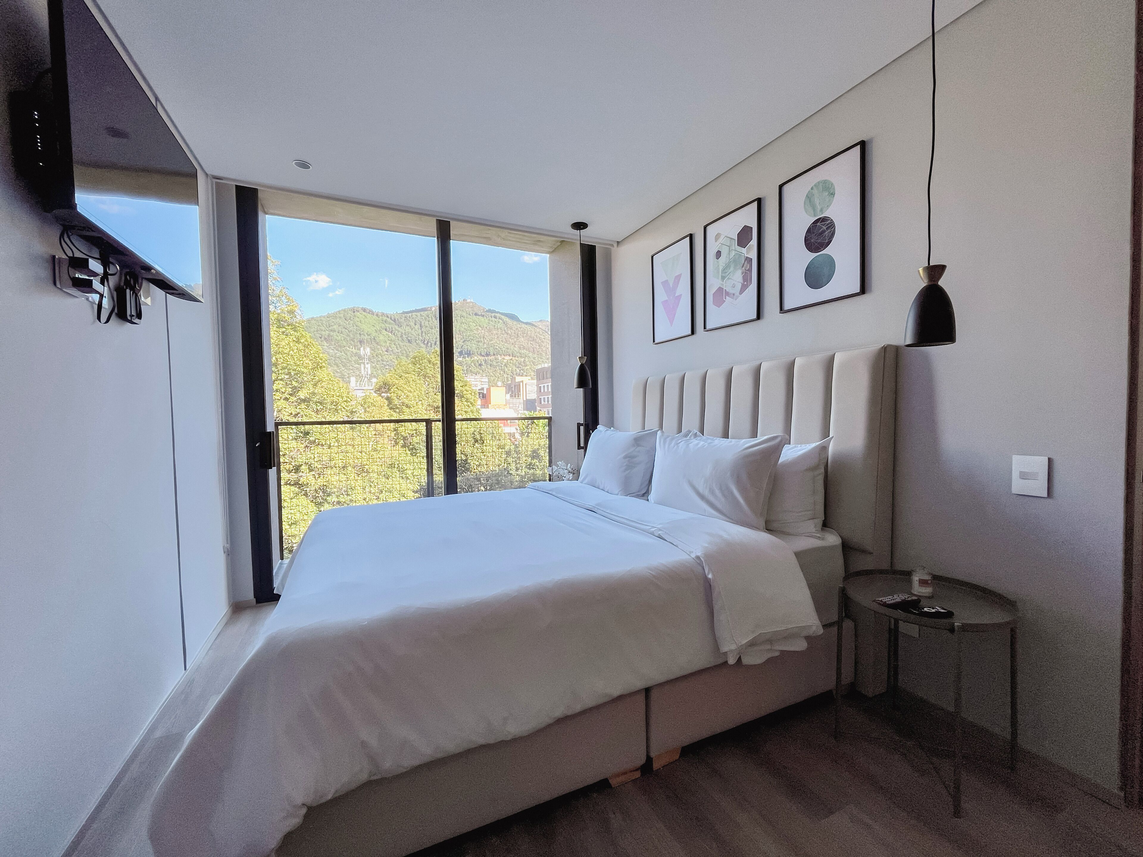 Un dormitorio moderno con una cama grande, una mesita de noche pequeña y vistas a un balcón.
