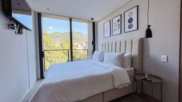 Un dormitorio moderno con una cama grande, una mesita de noche pequeña y vistas a un balcón.