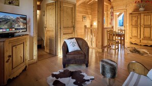 Ein Holzinterieur mit Fernseher, Ledersessel, Fellteppich und Holztüren.