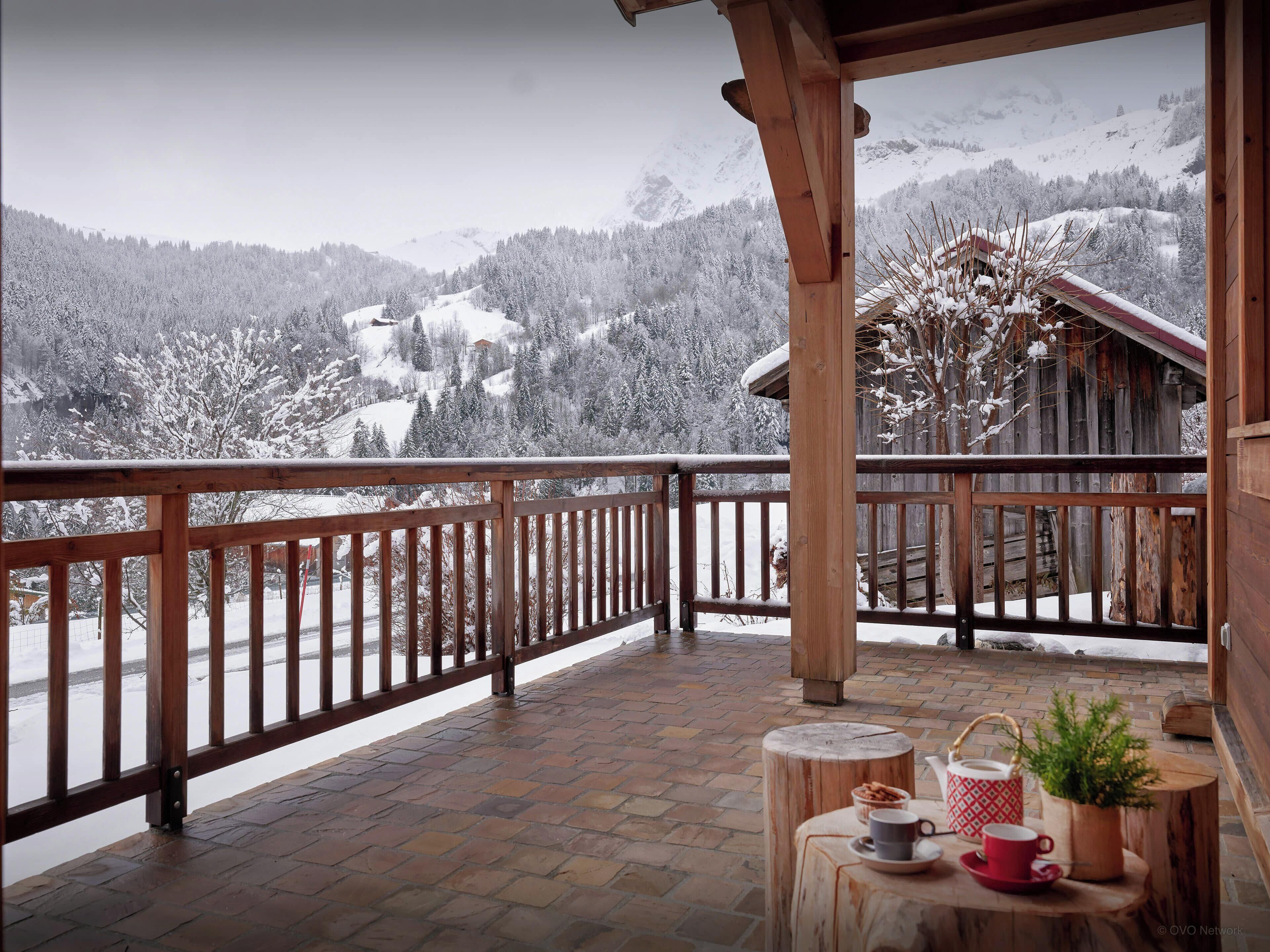 A wooden balcony with a view of snow-covered mountains.