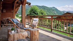 Eine Holzterrasse mit Liegestühlen und Blick auf eine gebirgige Landschaft.