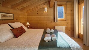 Ein gemütliches Schlafzimmer einer Holzhütte mit einem Bett, Kissen, einer Lampe und einem Fenster.