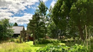 A garden with a wooden structure, a grassy area, and trees. - De Rulinen - SAINT CLET (SAINT CLET)