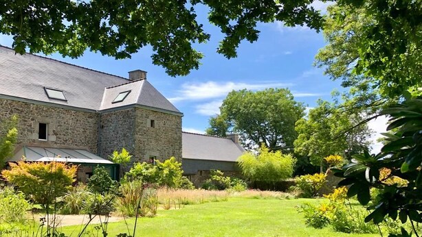 A stone building with a sloped roof, surrounded by a well-maintained lawn and various plants. - De Rulinen - SAINT CLET (SAINT CLET)