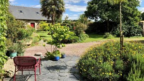 A garden with a stone pathway, a red bench, and various plants and flowers. - De Rulinen - SAINT CLET (SAINT CLET)