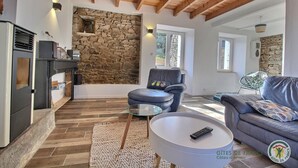 Una sala de estar acogedora con pared de piedra, chimenea, sofá, sillón y una mesita de centro.