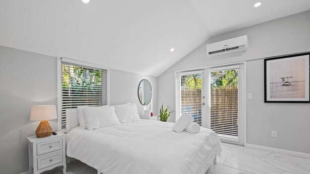 A modern bedroom with a large bed, white walls, and a ceiling fan. - Charming 2-bedroom house with WiFi and AC in welcoming Fort Lauderdale (Fort Lauderdale)