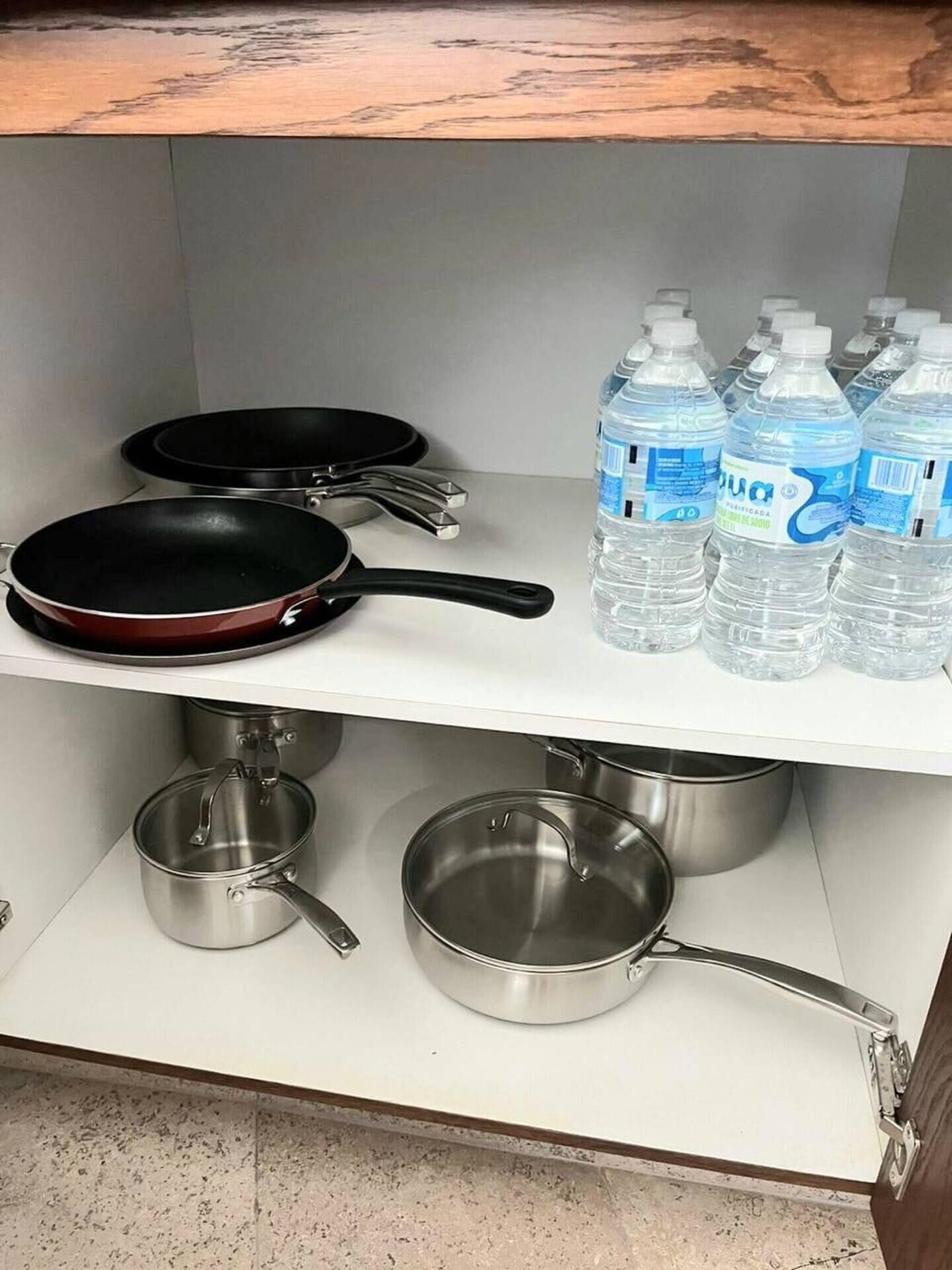 Eine Küchenregal mit Kochgeschirr und Wasserflaschen.