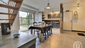 Een moderne keuken met een eethoek, grote ramen en een wenteltrap.