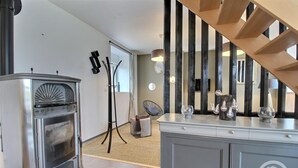 Een moderne keuken met een inbouwfornuis, een houten trap en een eethoek met een wit kastje en decoratieve objecten.