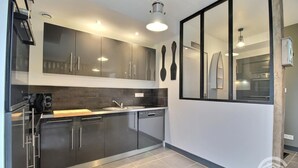 Een moderne keuken met donkere kastjes, een vaatwasser en een raam met uitzicht op de binnenplaats.