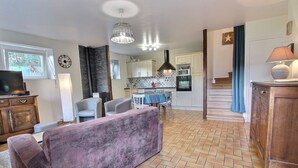 Un salon comprenant un canapé, un téléviseur et un coin repas avec des chaises et une table.