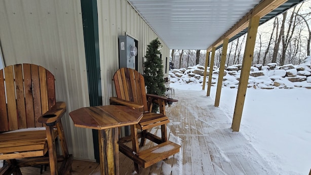 Un espace extérieur abrité, aménagé avec du mobilier en bois et dont le sol est recouvert de neige.