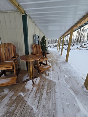 A covered outdoor seating area with wooden furniture and a snow-covered ground.