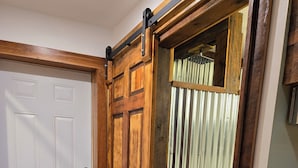 Une porte en bois avec un système de glissement de type porte de grange, une porte blanche avec une poignée de porte et une porte accordéon en métal.
