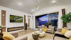 A modern living room with a fireplace, comfortable seating, a large TV, and a view of the outdoors.