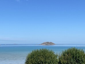 A coastal landscape with a clear sky, a body of water, and a distant island.