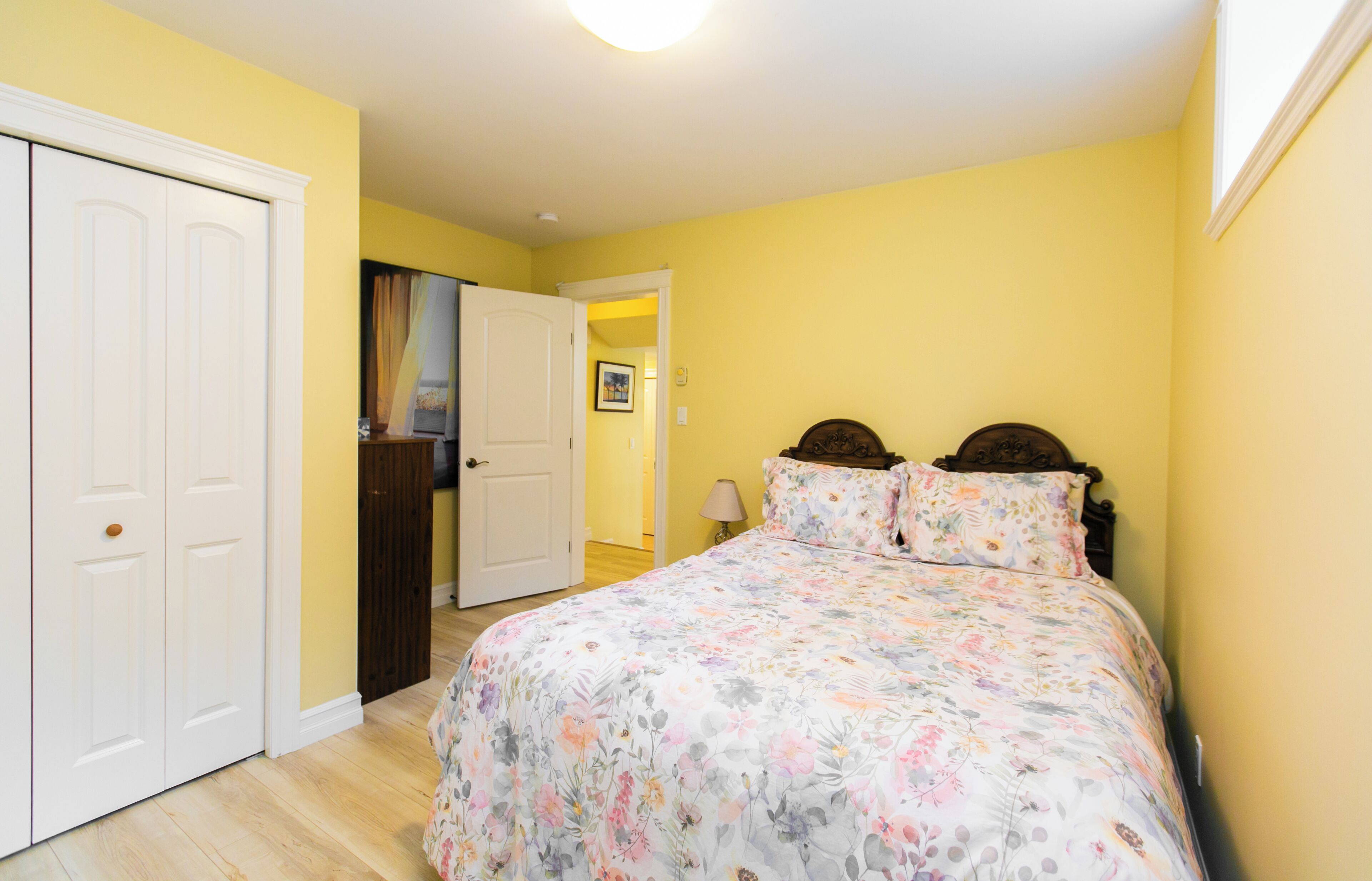 A bedroom with a floral bedspread, a wooden headboard, and a white door.