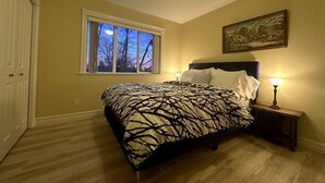 Une chambre à coucher avec un lit, des lampes de chevet, une fenêtre et un tableau au mur.