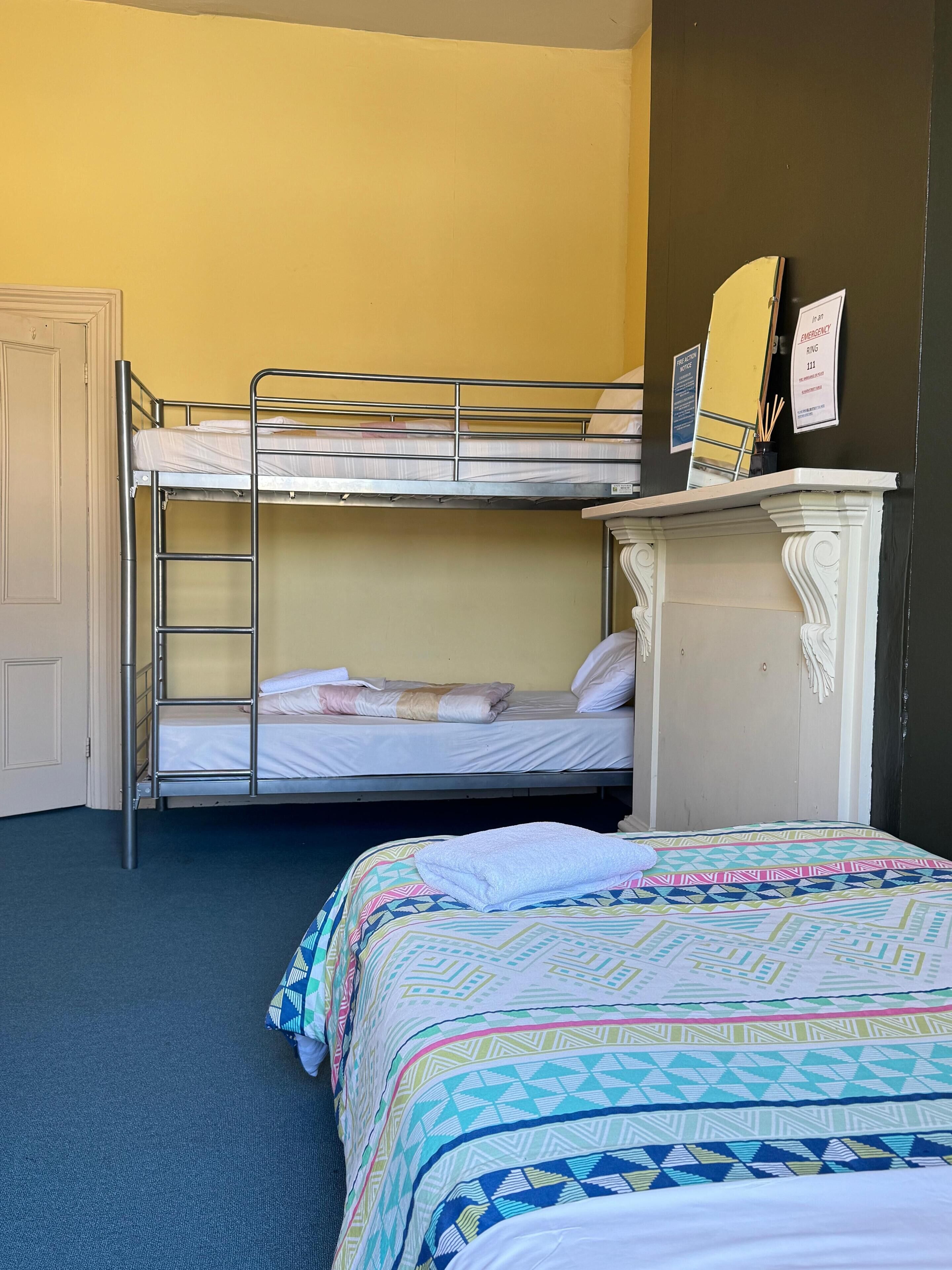 A room with bunk beds, a dresser, and a bed with a patterned bedspread.