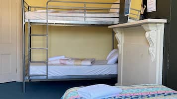 A room with bunk beds, a dresser, and a bed with a patterned bedspread.
